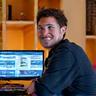Glad hobbymusiker sittende i sitt hjemmestudio med et smil